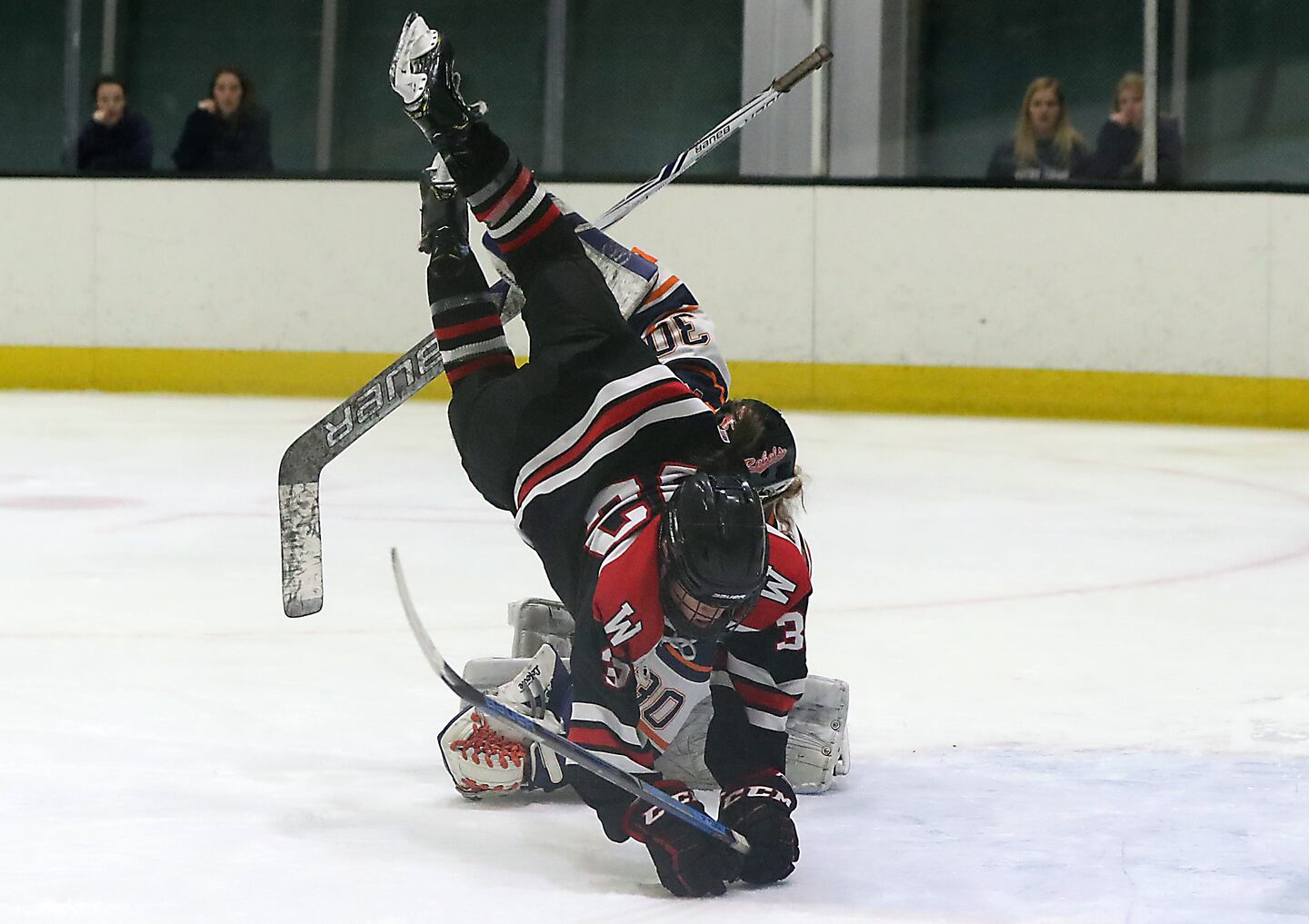 Walpole goalie Kiera McInerny upends Wellesley’s Lulu Rourke after stopping her penalty shot in the second period.