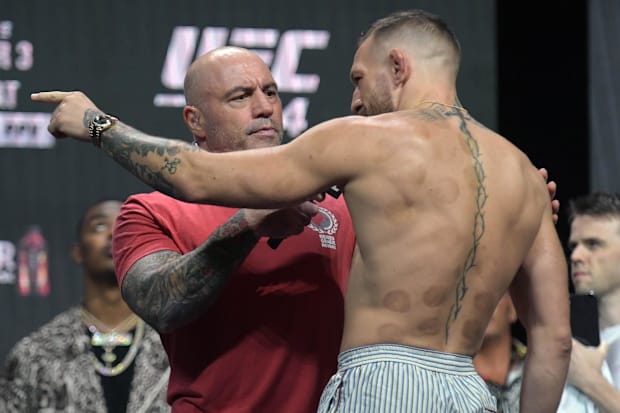 Conor McGregor motions toward Dustin Poirier while being interviewed by Joe Rogan during weigh-ins for UFC 264.